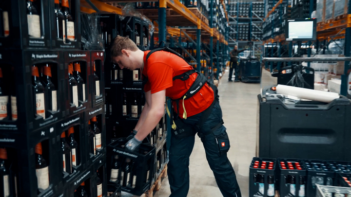 Ein Mitarbeiter der Brauerei S. Riegele nutzt das BionicBack Exoskelett beim Heben schwerer Getränkekisten. (Bild: Htrius)
